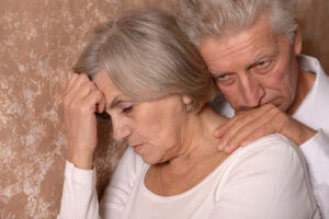 Close-up portrait of a sad elder couple on brown background