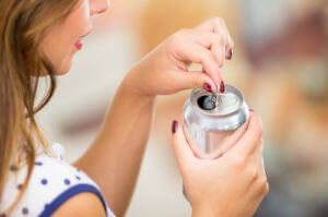 a woman opens a can of soda