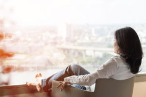 a woman lounges in a chair while looking out the window