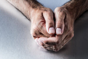 a man holds his hands together and rests them on a table