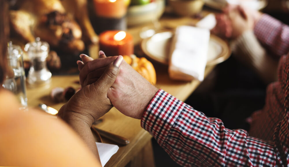 people hold hands and pray at thanksgiving
